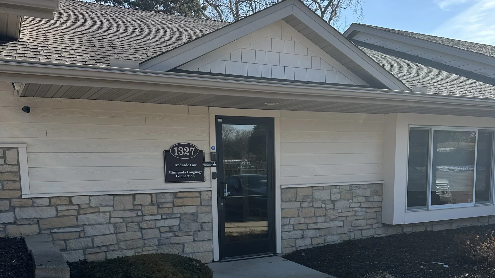 Front facade and entrance of the Andrade Law PLLC personal injury law office at 1327 County Rd D Cir, Saint Paul, MN, with the building sign listing Andrade Law