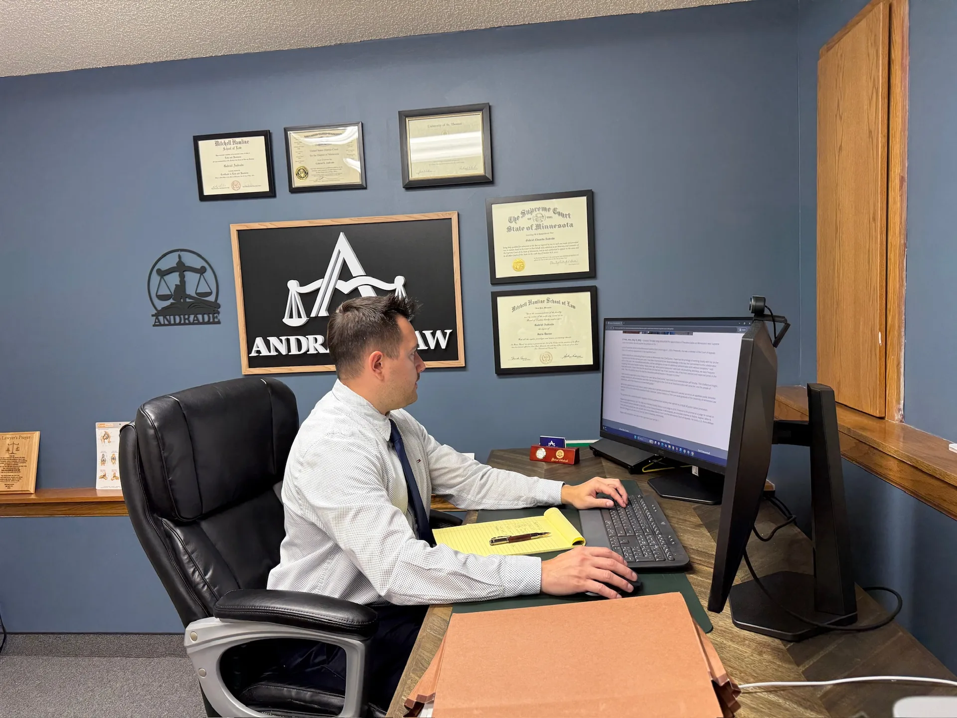 Attorney Gabe Andrade reviewing a case file at his desk in the Andrade Law office in Saint Paul, Minnesota